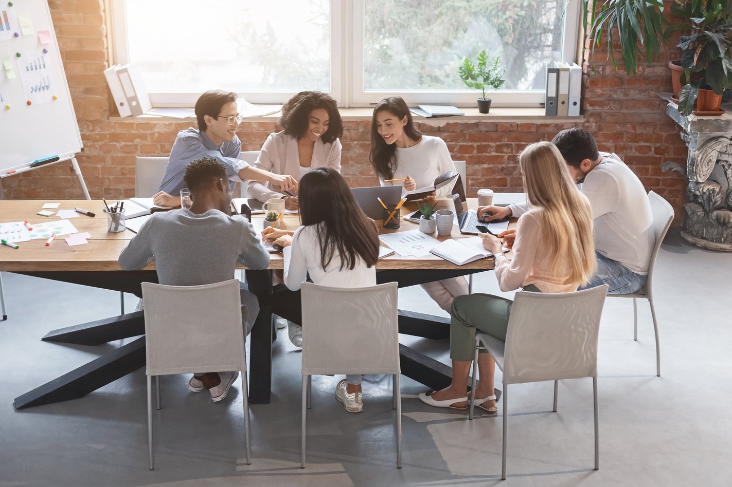 Friendly business team sitting around table, having meeting